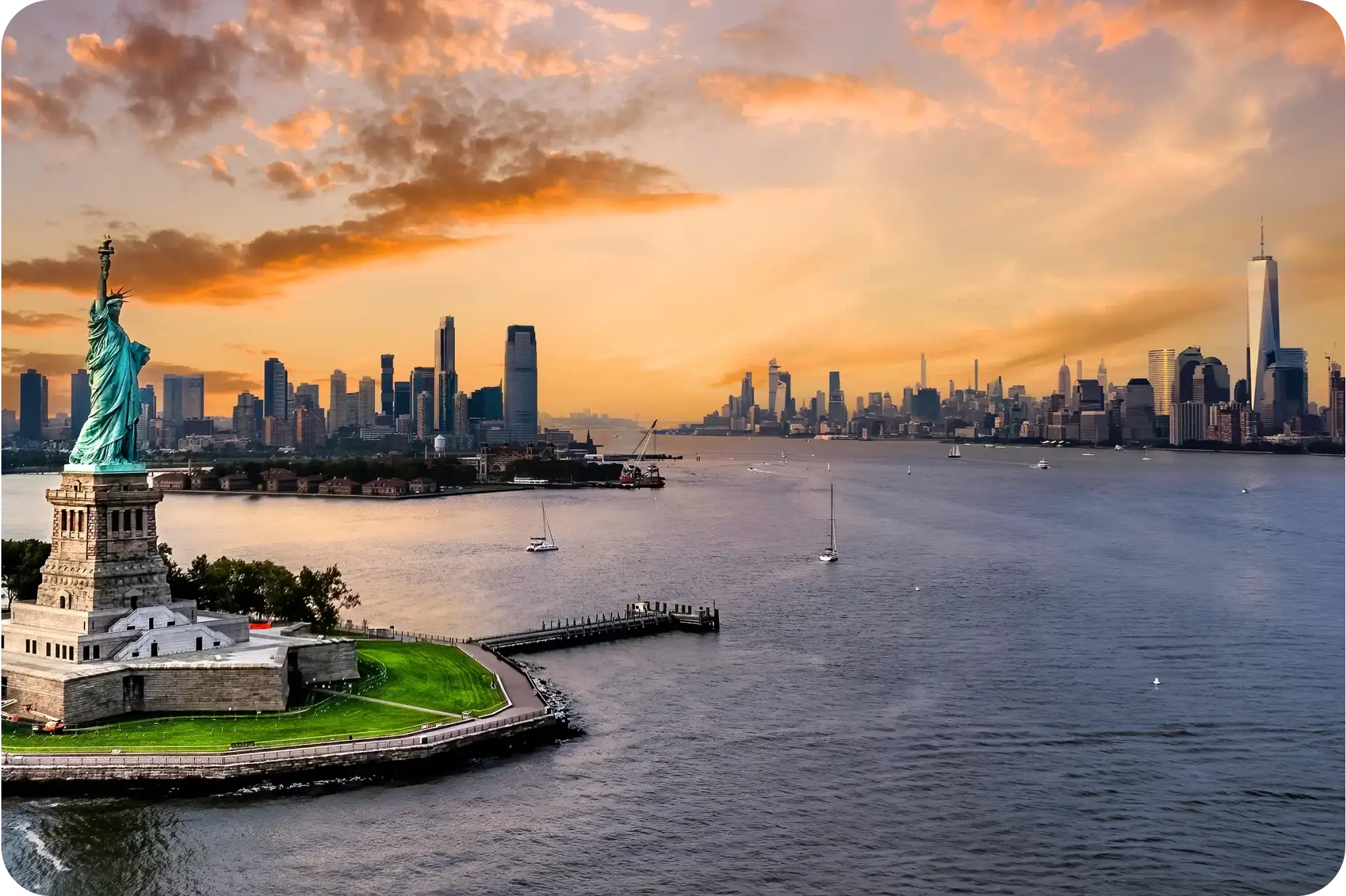 Statue of Liberty at sunset with New York City skyline in the background