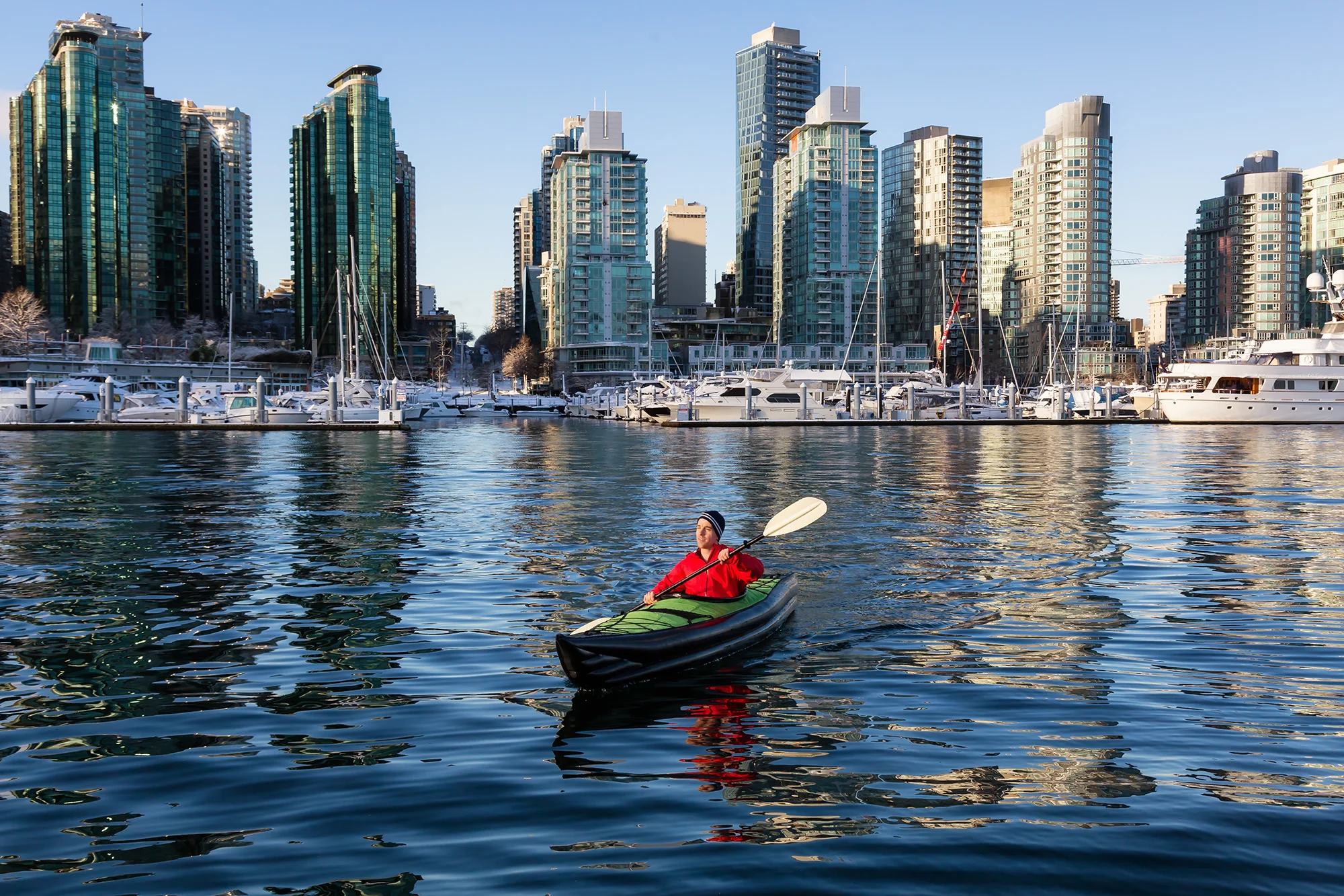Man on kayak in front of cityscape of Vancouver, Canada